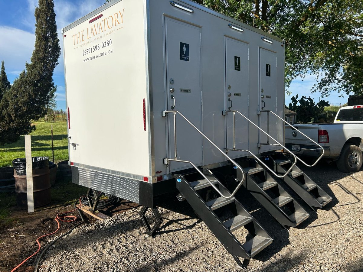 White 3 station restroom trailer staged on pavement, a mid size rental for weddings and campus projects