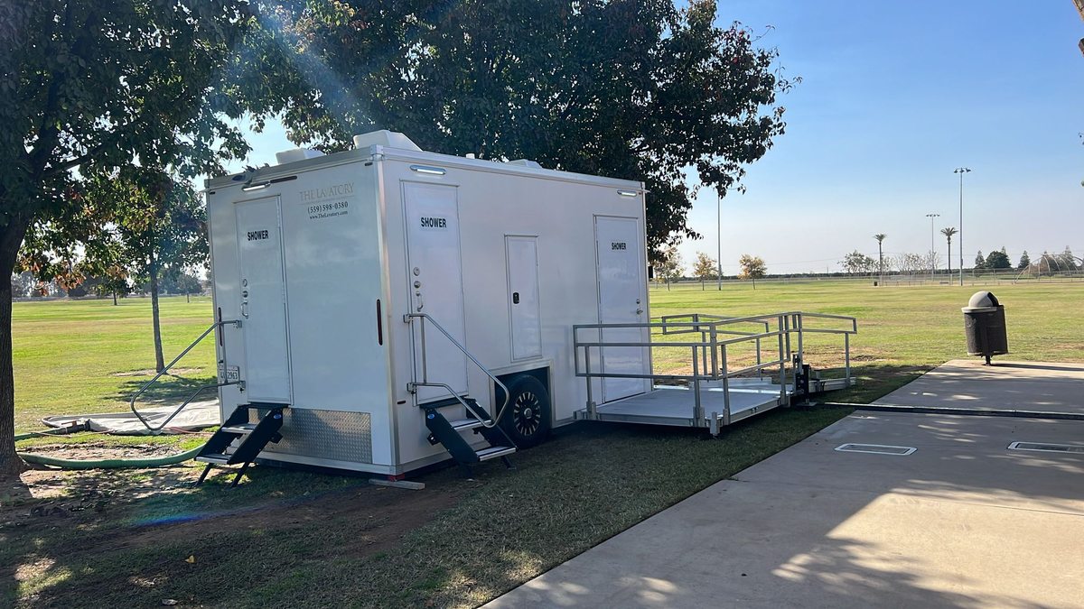 Accessible shower trailer rental with ramp entry beside two standard private stalls