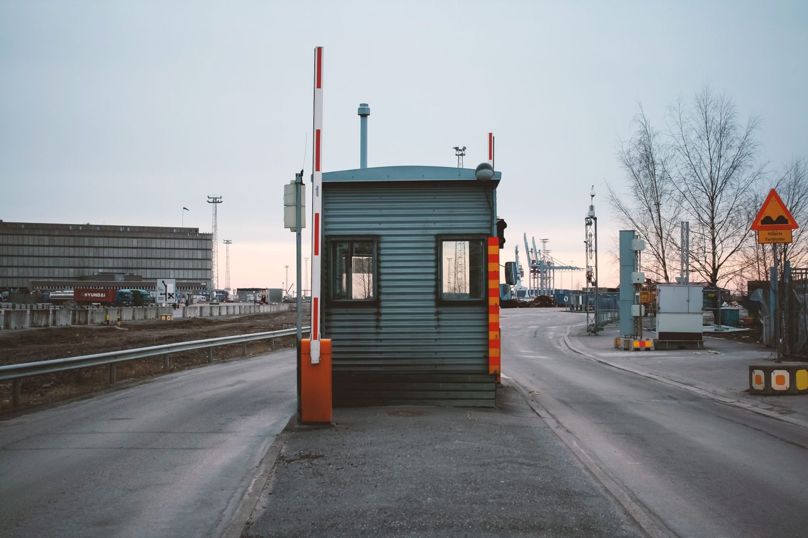 A vehicle checkpoint lane with barriers at a facility entrance