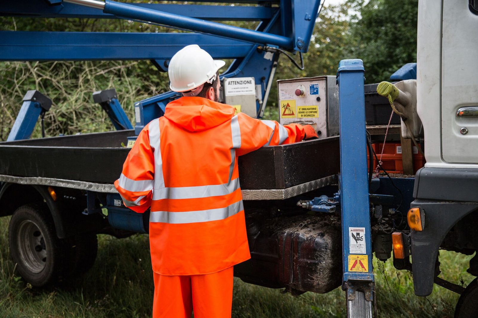 A worker in high visibility gear at the controls of a service truck