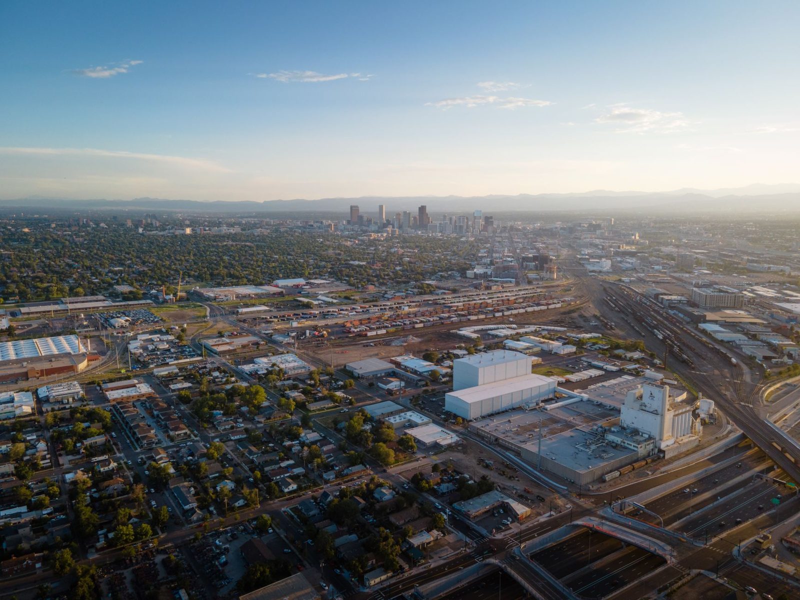 An aerial view of Denver's neighborhoods and downtown skyline with the Front Range on the horizon