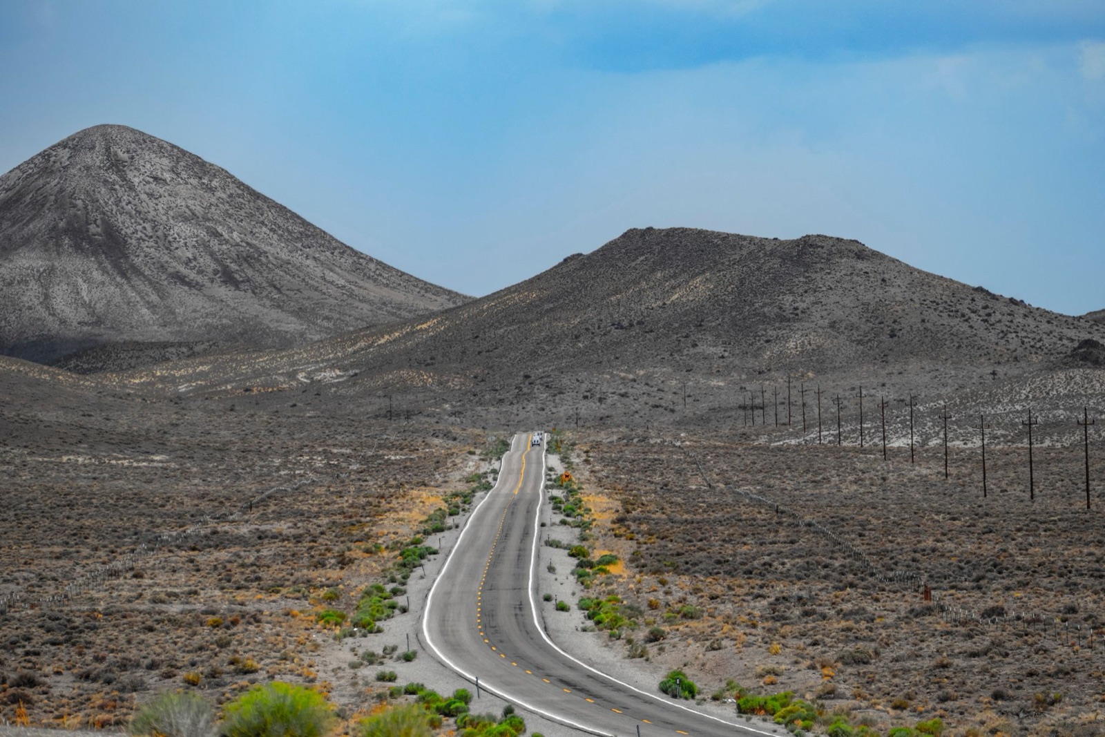 A two-lane road climbing between bare, dry desert mountains