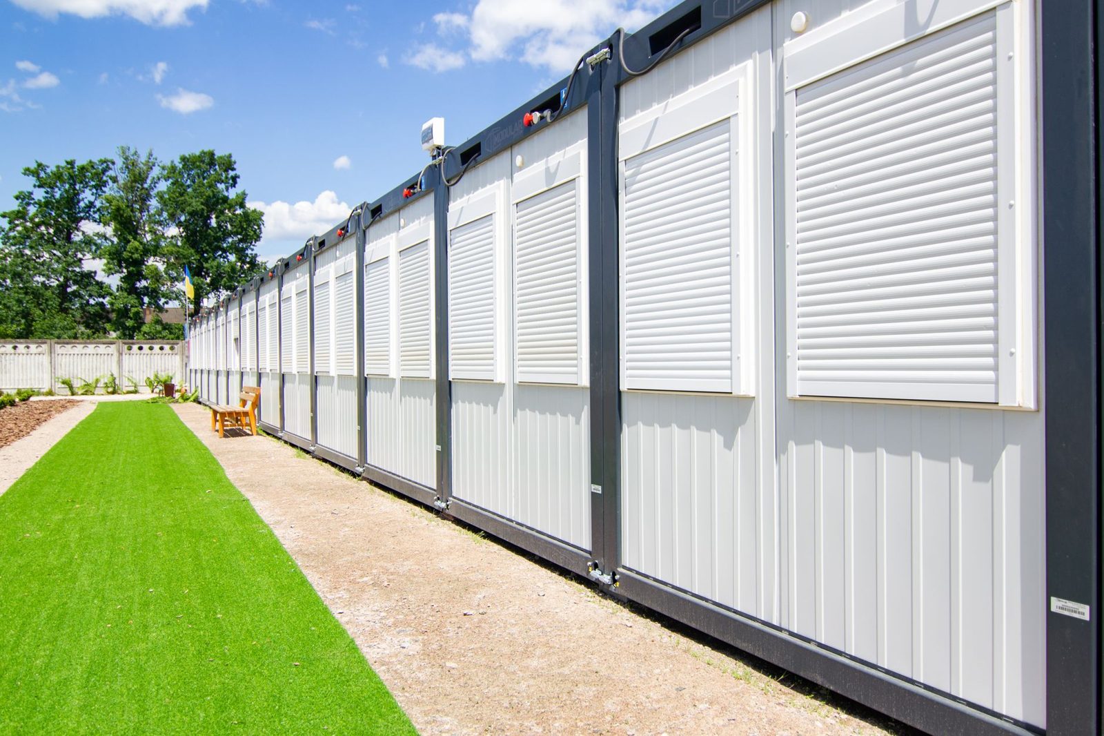 A long row of modular housing units beside a lawn