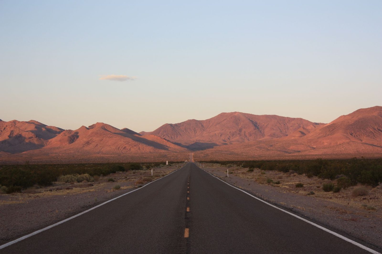 A desert highway running toward bare mountains, the kind of open country large training areas use