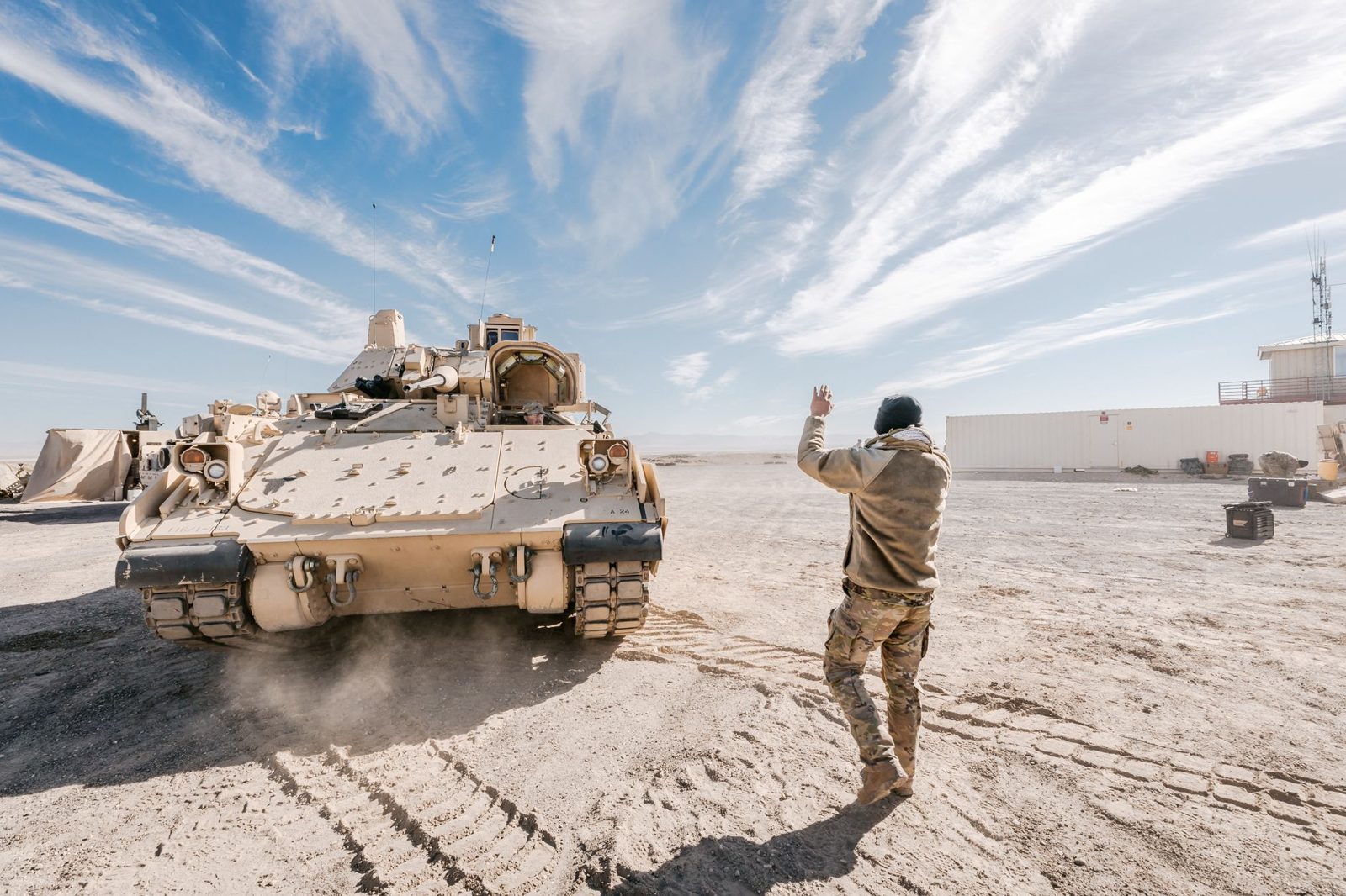 Military vehicles moving across open desert training ground