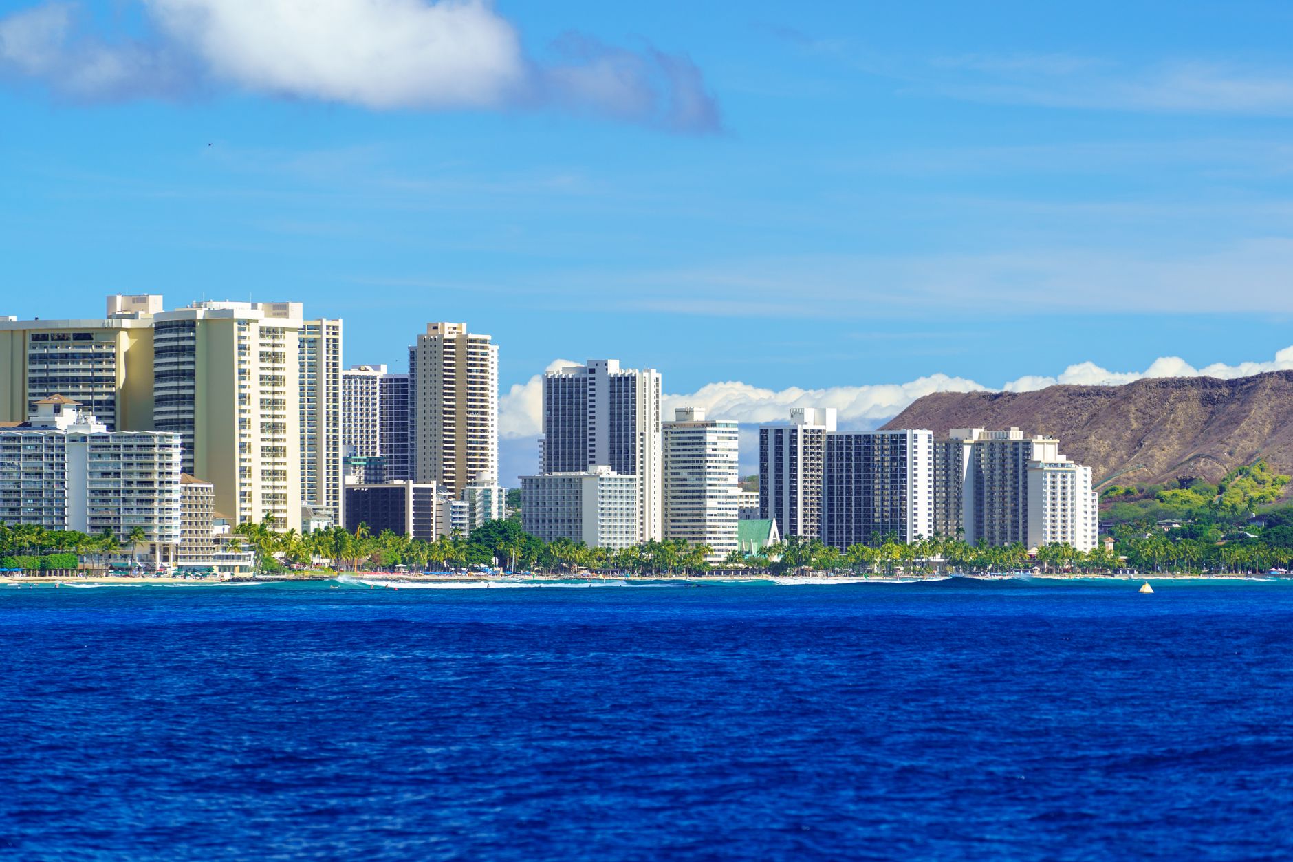 Waikiki high-rise skyline along the shoreline with Diamond Head crater behind it, the dense urban core of Honolulu where shelter and disaster-response sites stand up on Oahu