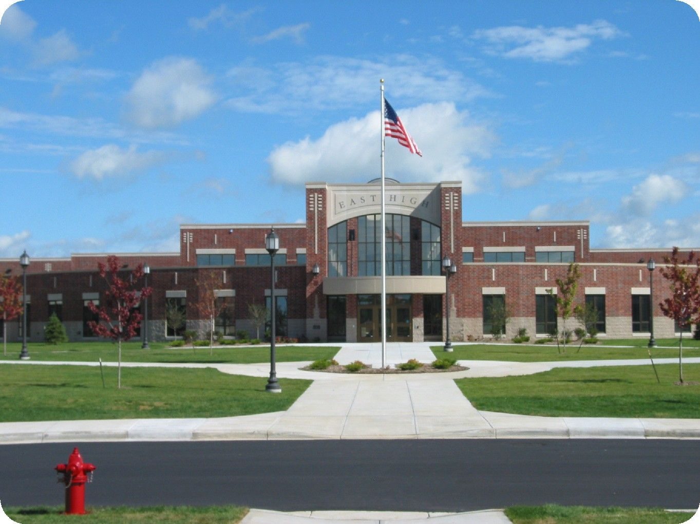 American high school campus building with flag on a clear day