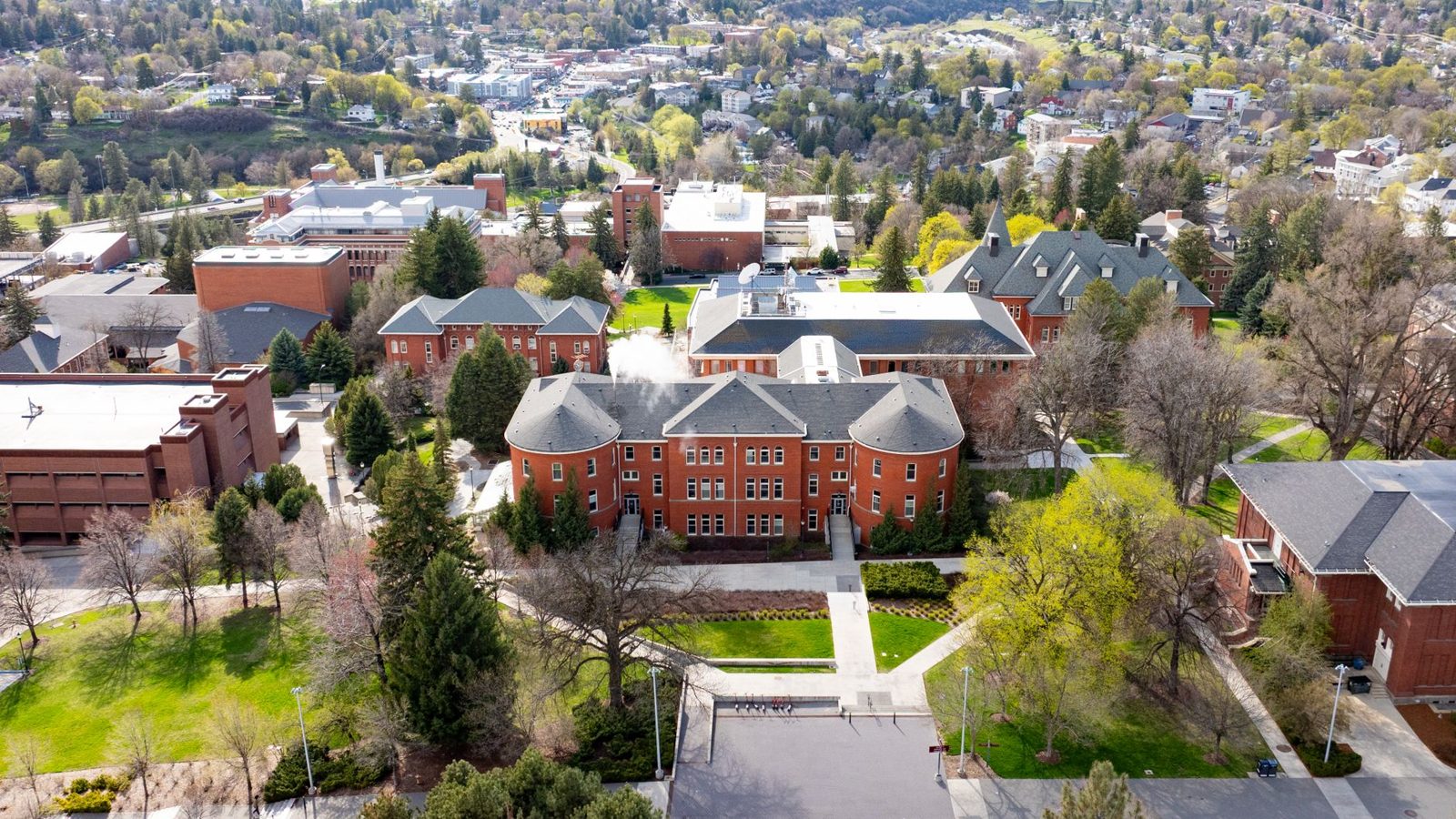 An aerial view of a college campus with brick buildings and trees