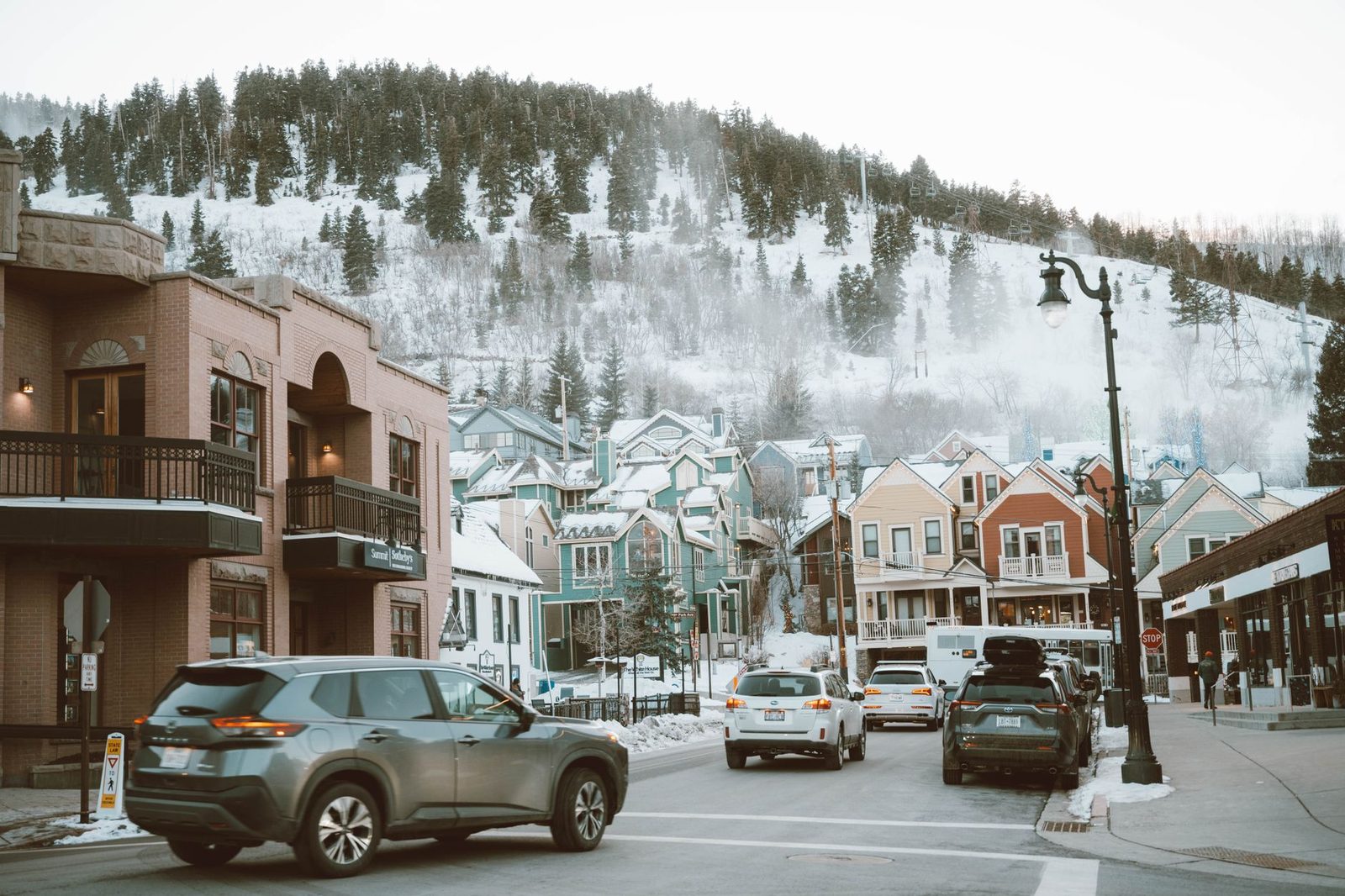 A snowy Park City street below ski slopes and pine-covered hills