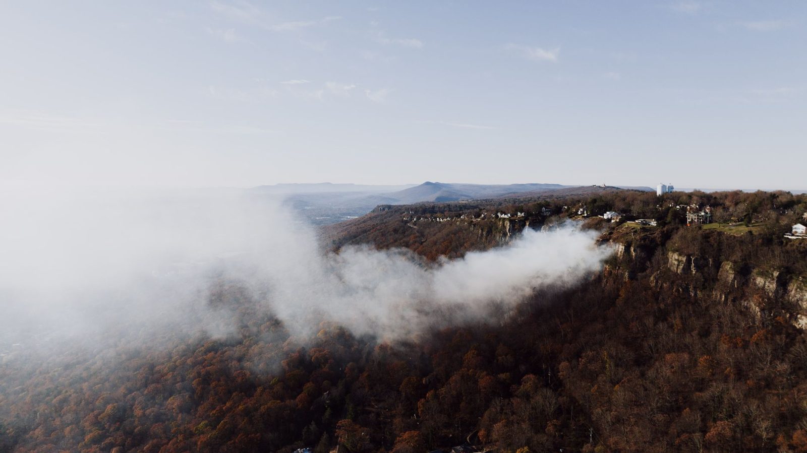 Smoke drifting over a forested ridge at sunset